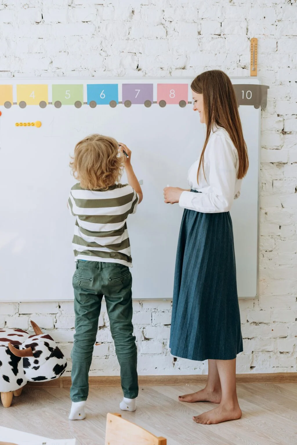 A teacher and young student writing together at a whiteboard